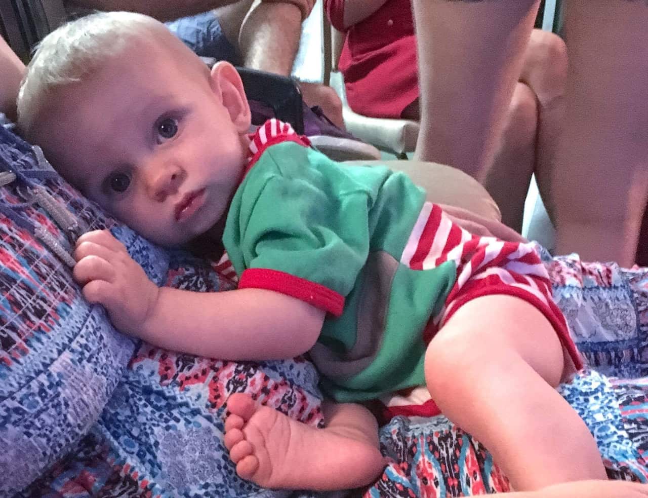 A baby in a Christmas outfit lying on a woman's stomach