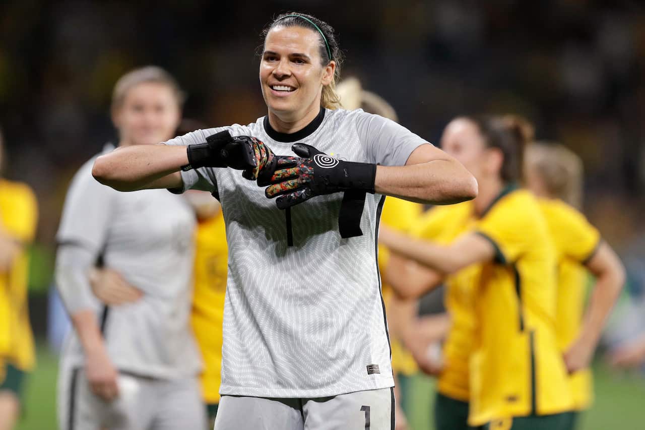 A woman in a grey football uniform pulling at her gloves