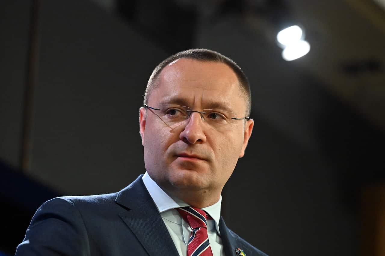 Man in glasses and a suit looks out from the camera.