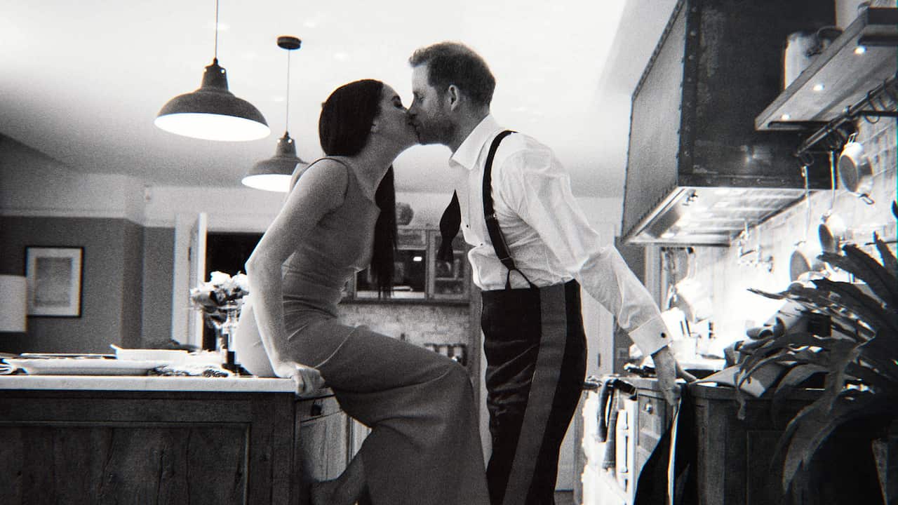 A black and white photo of Prince Harry and Meghan Markle kissing in a kitchen