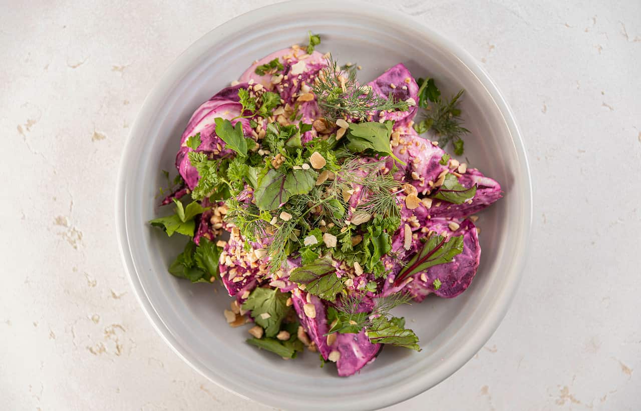 Roasted beetroot with horseradish crème fraiche and herbs in a bowl.