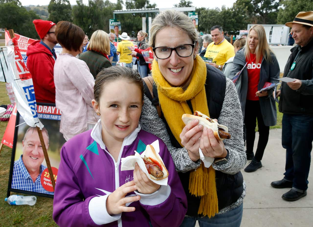 Hannah Jackson and Jane Harris pose for a photograph with their sausage sizzles.
