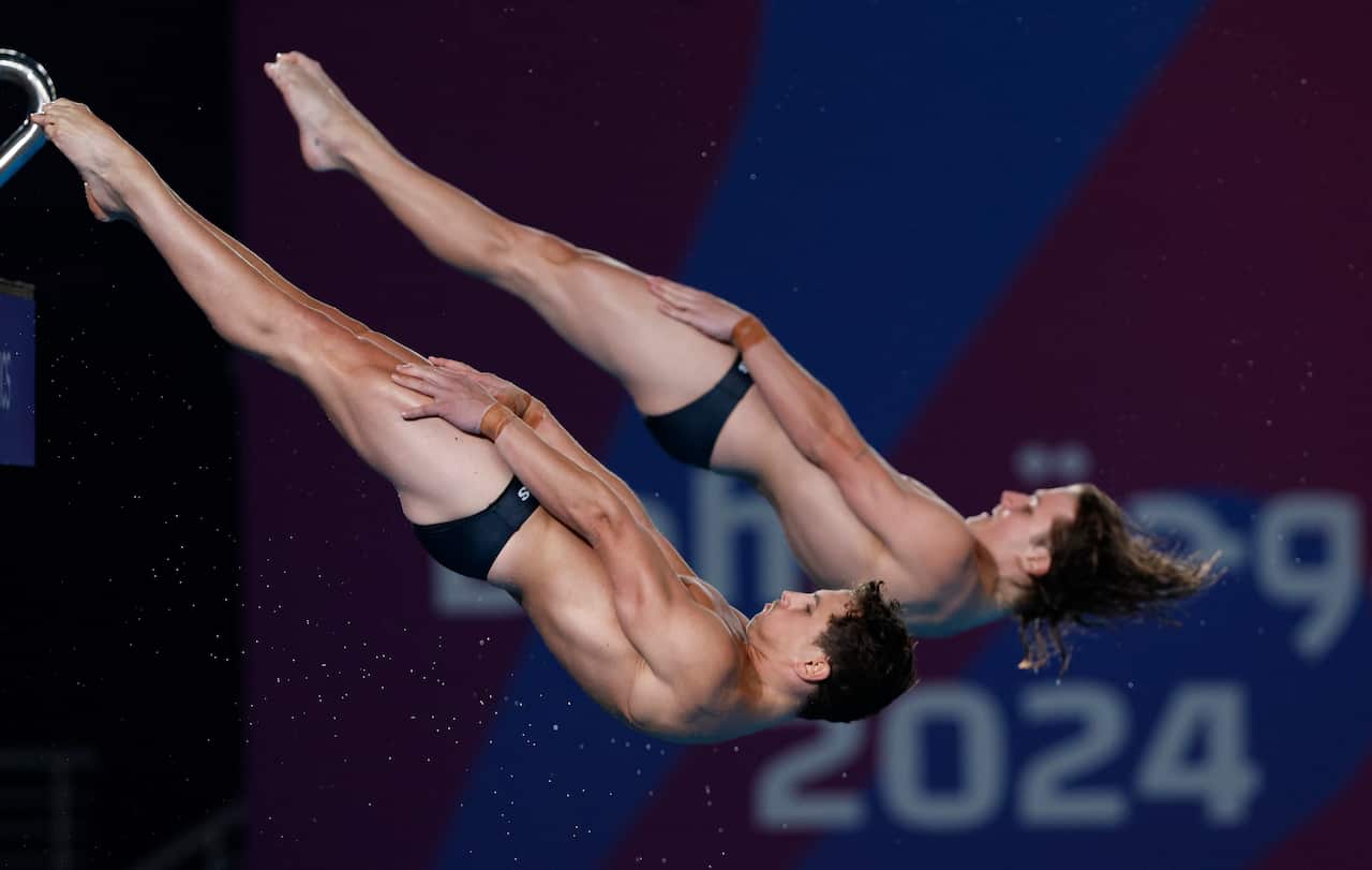 Two male divers upside down in the air