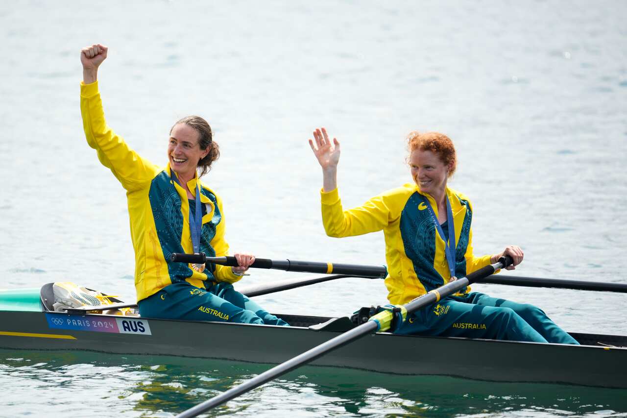 Jess Morrison and Annabelle McIntyre sitting on their boat and waving. 