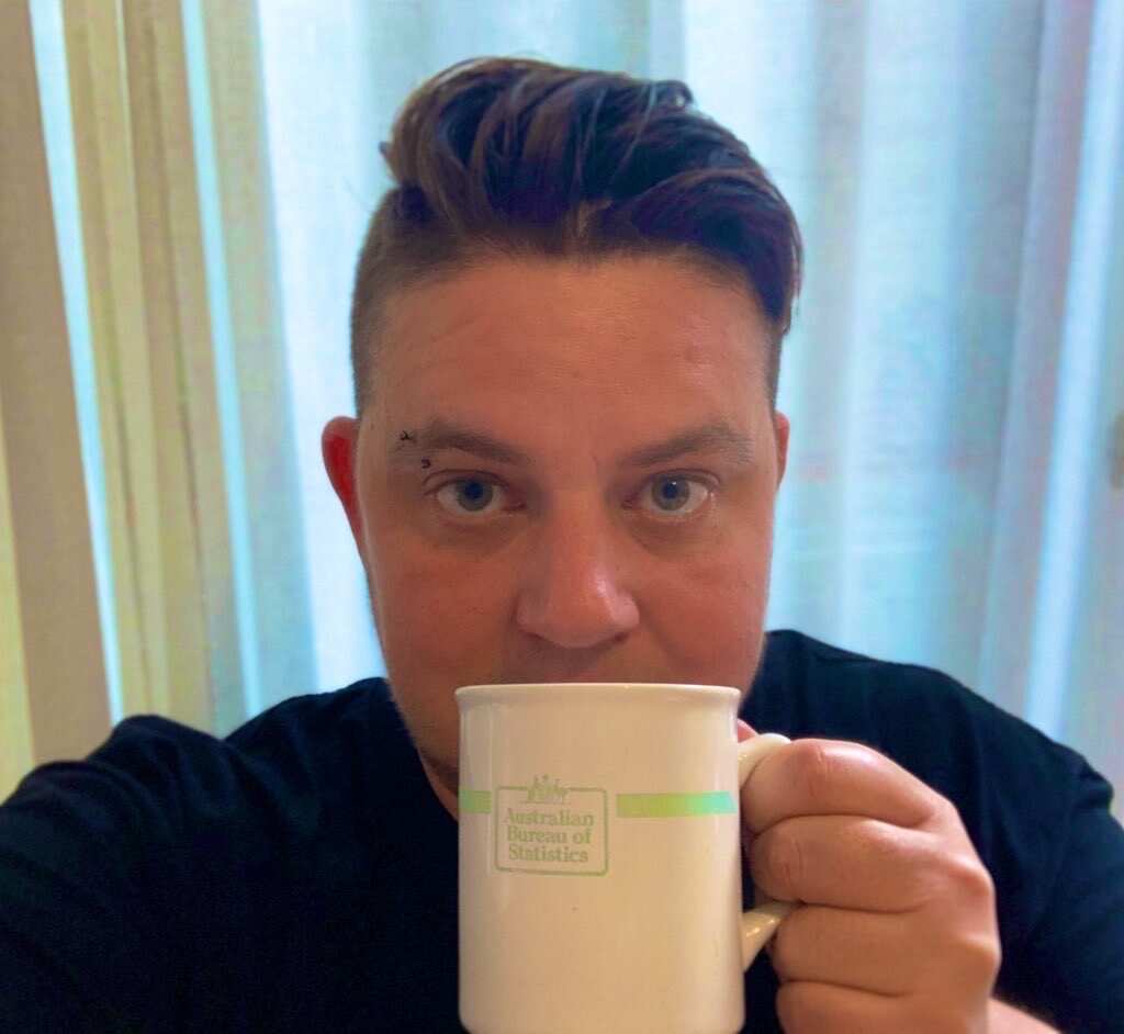 Switchboard CEO Joe Ball holding an Australian Bureau of Statistics mug up to his face.