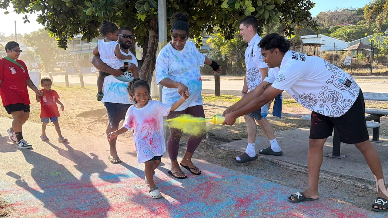Young and old run along the islands water front while event staff throw colourful flour at each other.