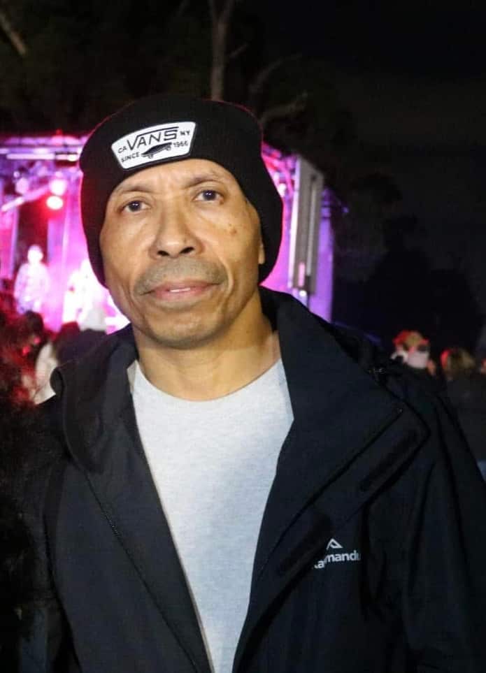 A man wearing a hat looks to the camera.