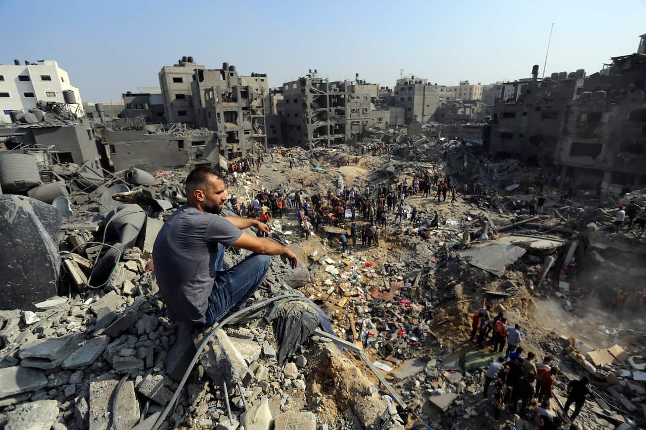 A man sitting in a pile of rubble looking down at another crowd of men.