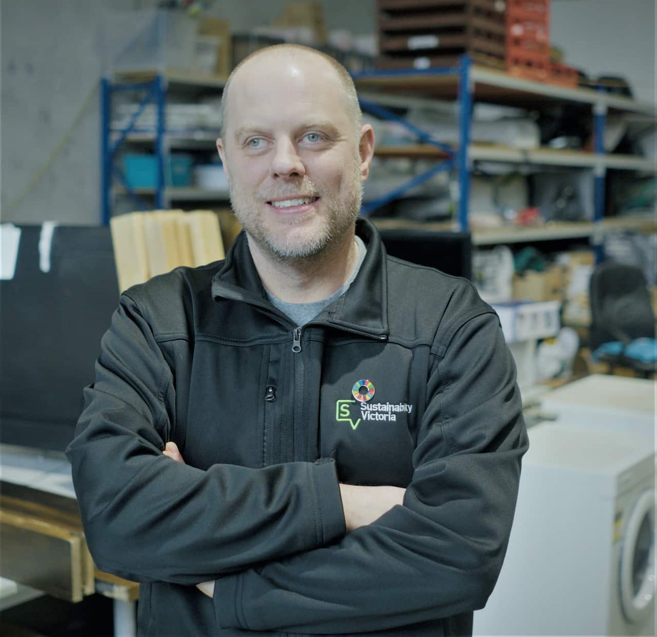 A man standing in the warehouse in a grey jacket.