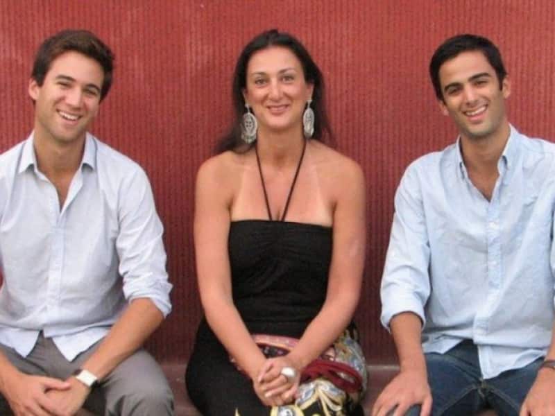 Woman in a black halter neck top and large earrings with two young men in plain white shirts sitting by her sides