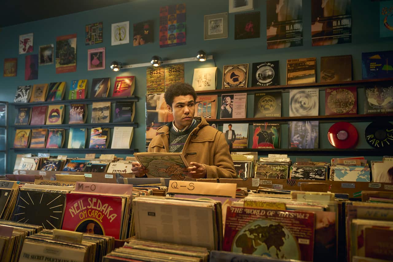 A young man stands in a record store. 
