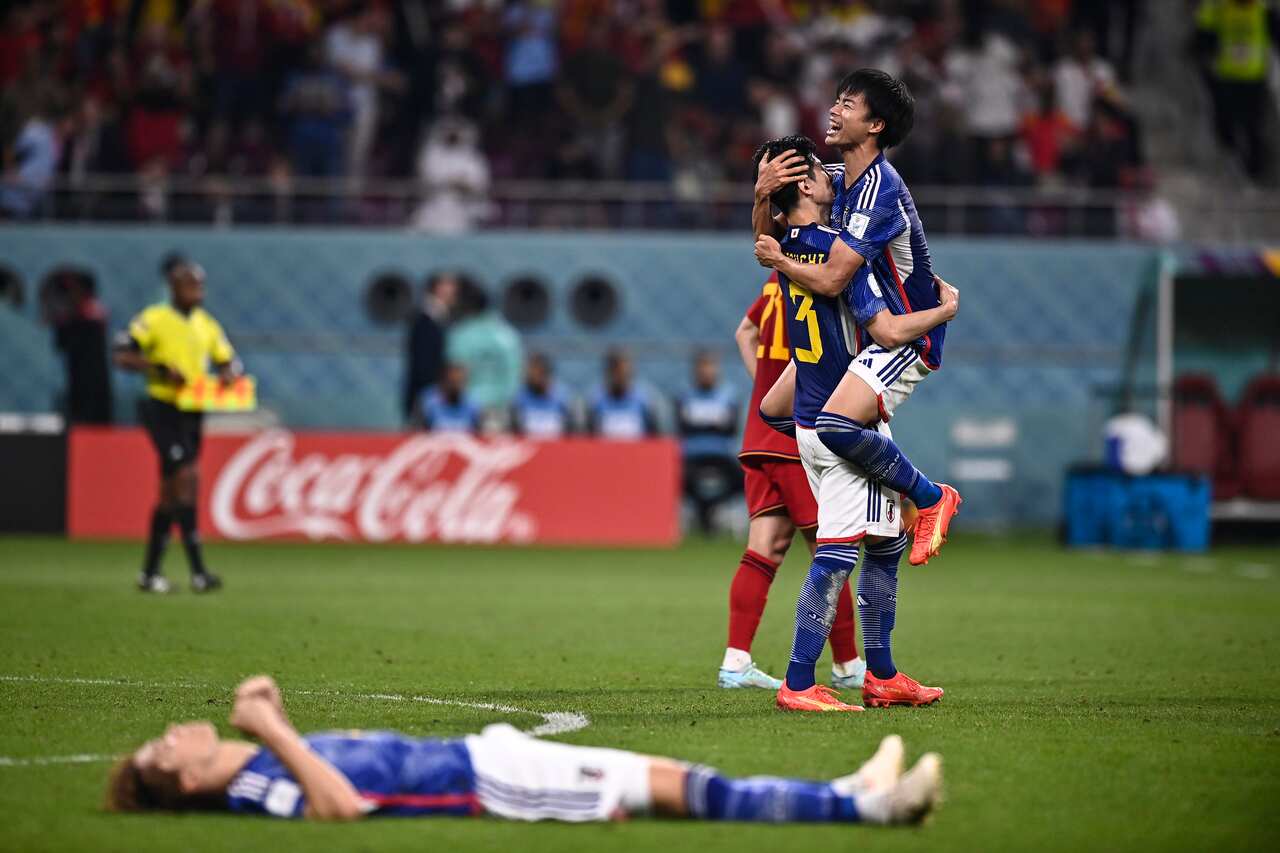 Players hug and lay down on the football field. 