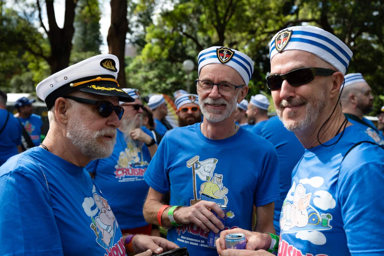 A group of men in sailor hats stand amicably in frame.