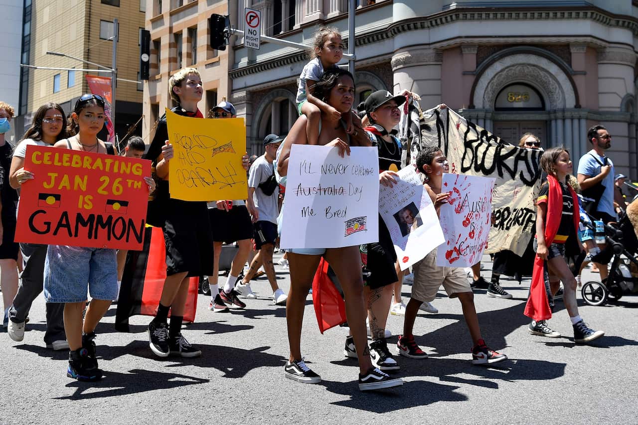 Protesters hold placards as they march through the Sydney CBD.