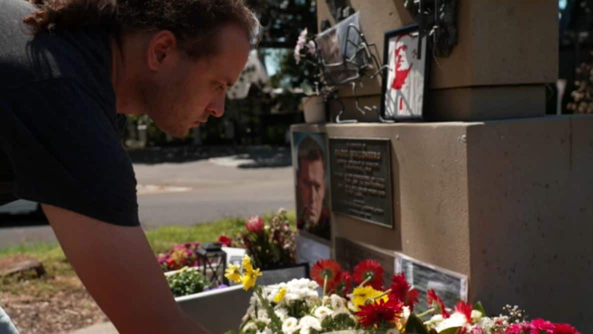 A man lays flowers at a memorial.
