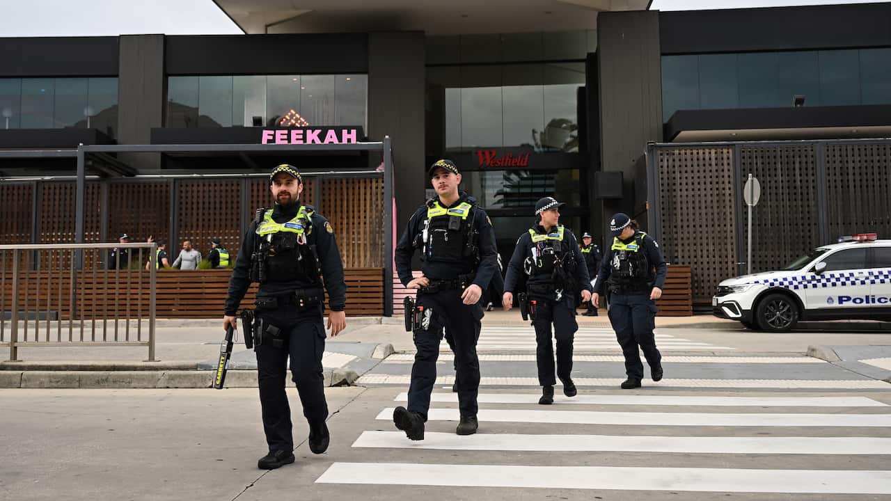 Four police in uniform walking along a pedestrian crossing.
