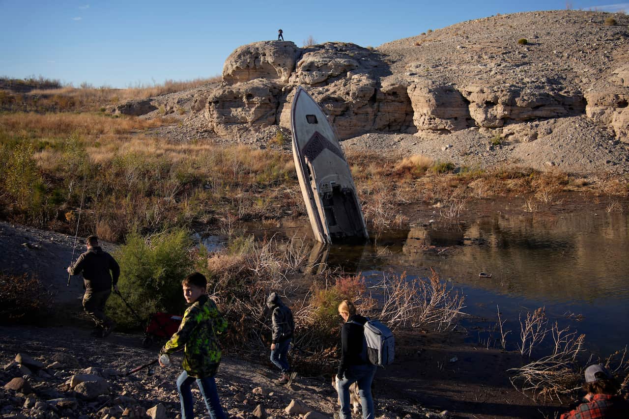 A boat sticks out of a small pool of water along the shoreline of Lake Mead, which was formed by the Colorado River.
