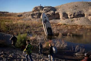 A boat sticks out of a small pool of water along the shoreline of Lake Mead, which was formed by the Colorado River.