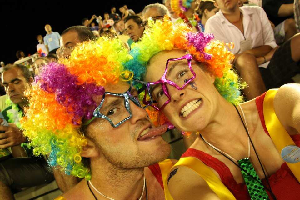 Sarah Rus smiles with her former boyfriend. They're wearing colourful wigs outside.