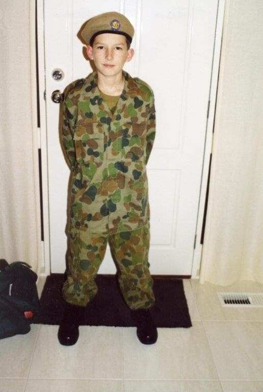 A young boy dressed in an army uniform. 