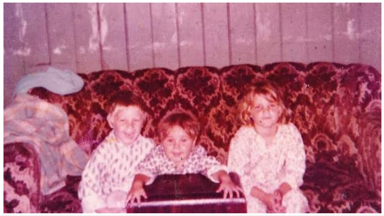 Three children in pyjamas sit on a lounge chair. 