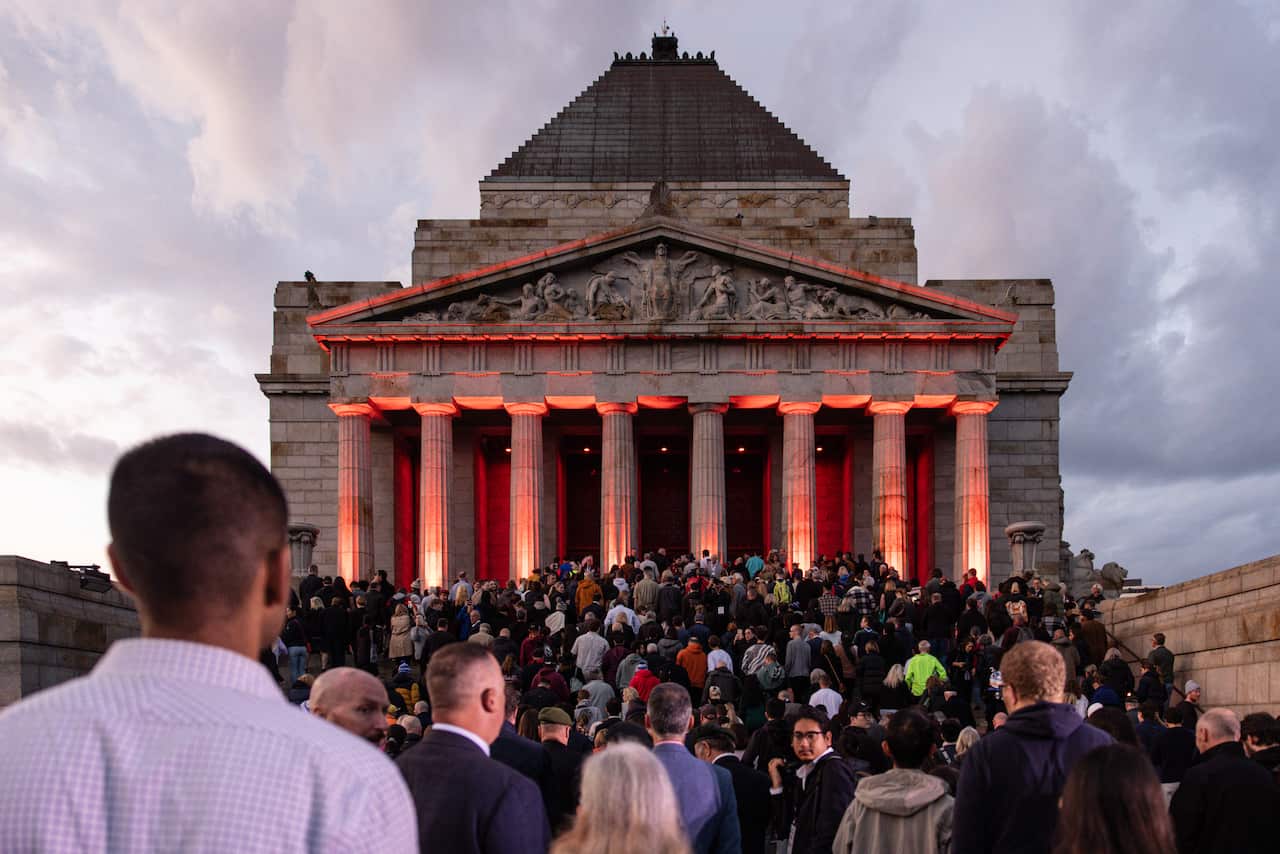 a large group of people gather outside a memorial
