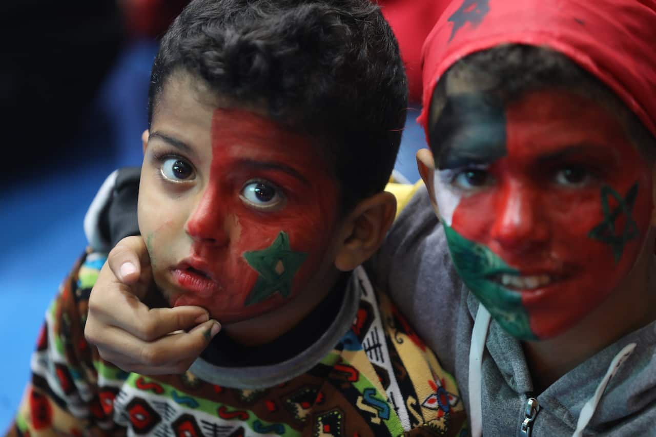 Palestinian football fans with faces painted in the colours of the Palestinian and Moroccan flags watch the World Cup match between Portugal and Morocco in Gaza city on 10 December 2022.