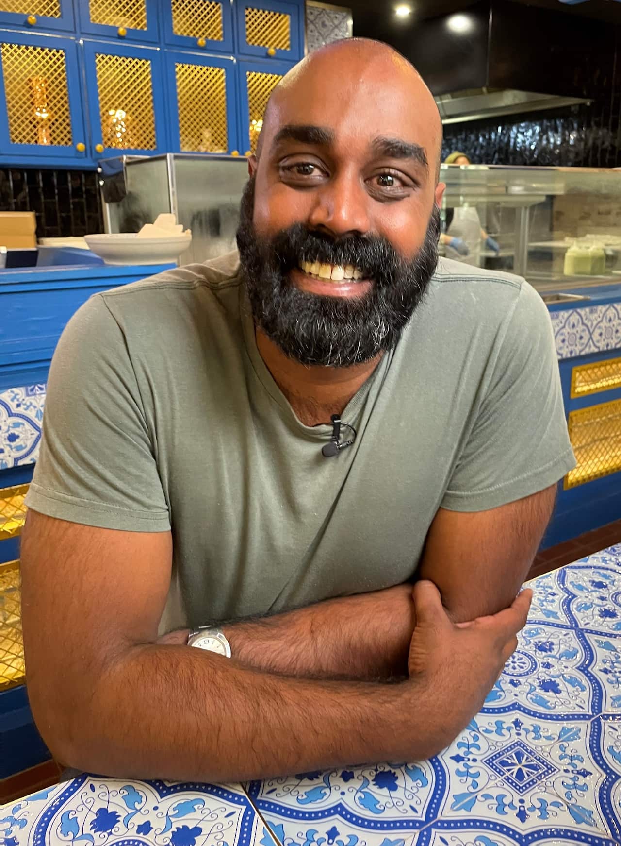Shaun Christie-David wearing a t-shirt and sitting with his arms crossed leaning on a table