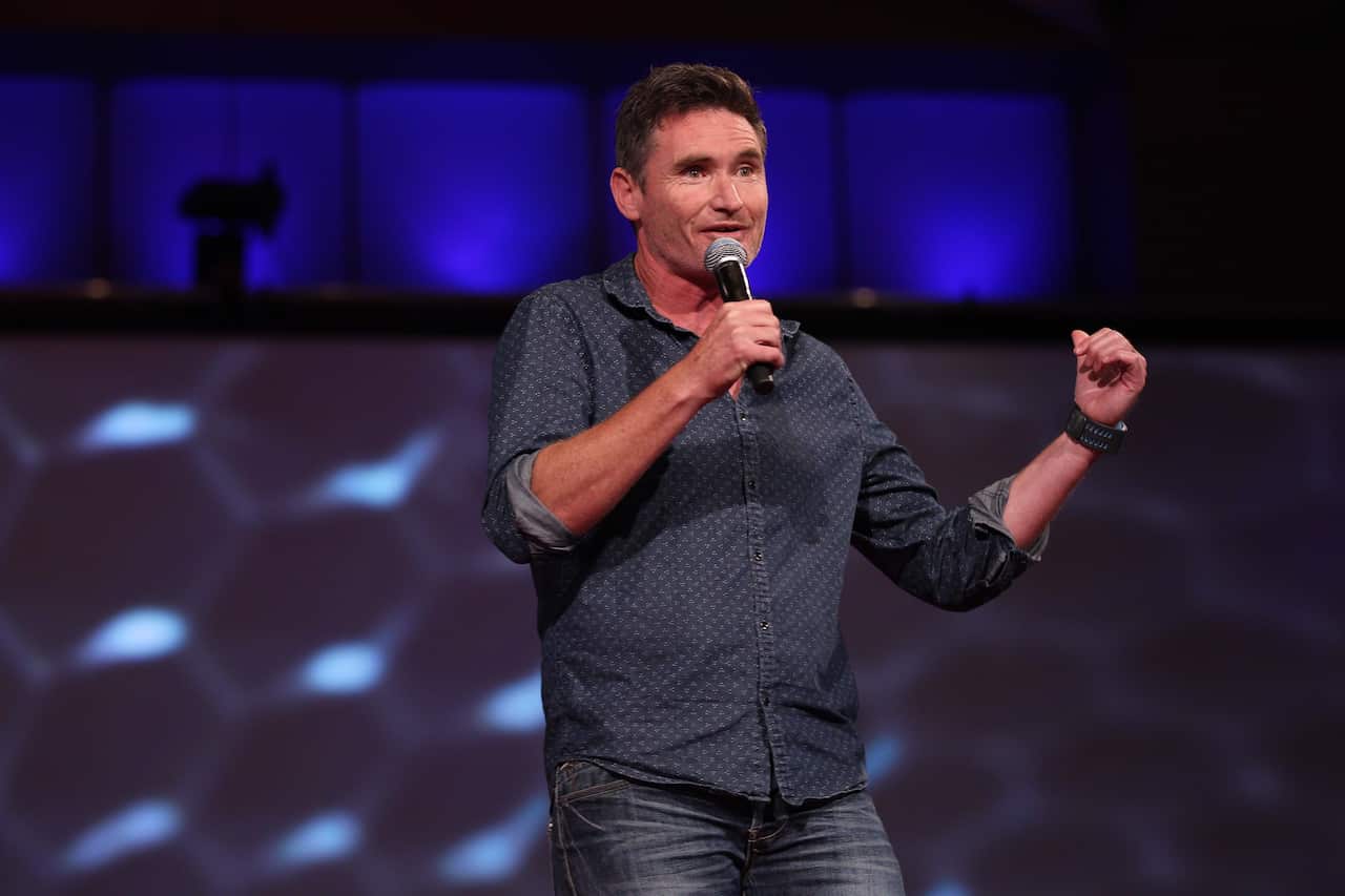 Dave Hughes holding a microphone and talking on stage
