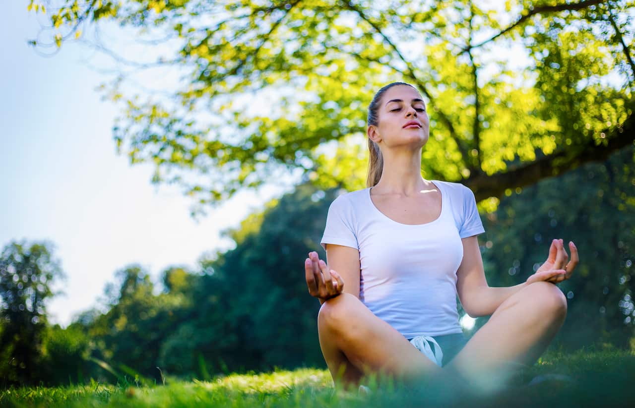 Beautiful woman meditating in city park