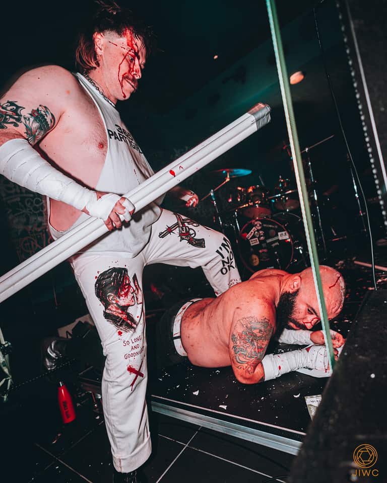 A man standing on anothers back while holding a light tube.