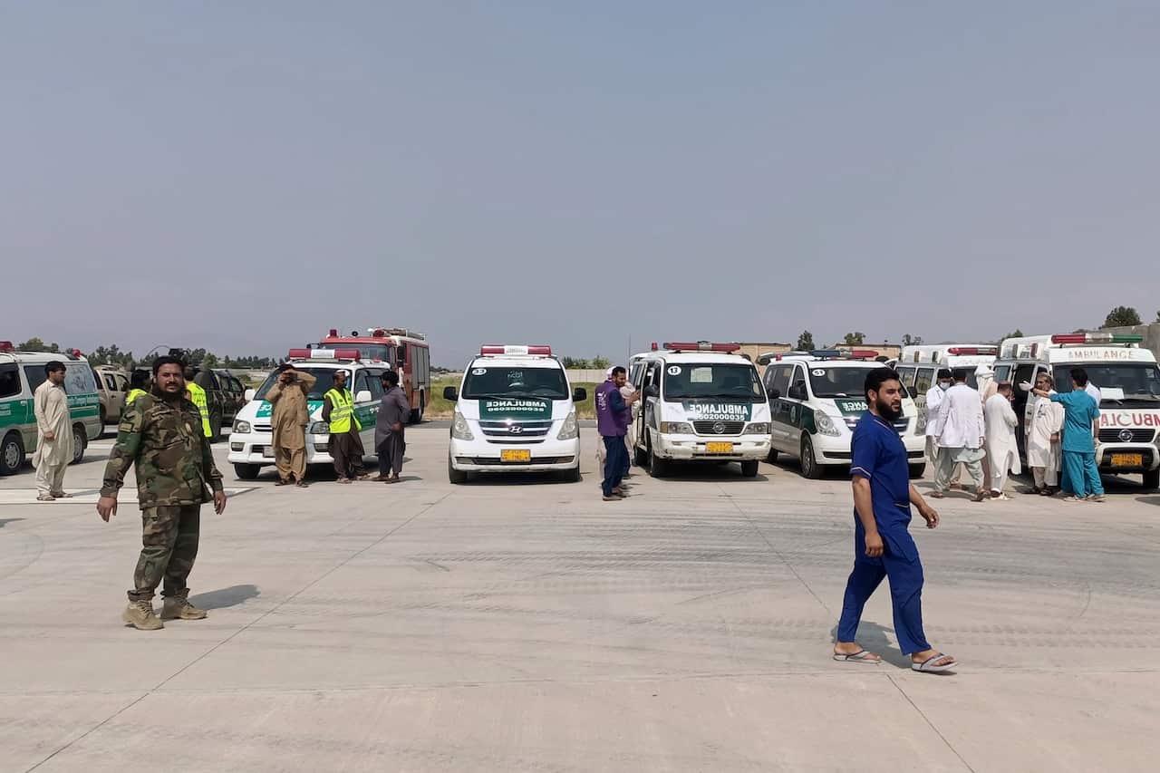 Two people walking in front of a row of ambulances.
