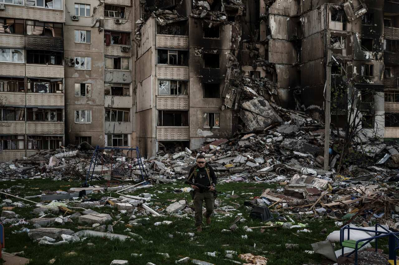 A Ukrainian serviceman walking amid the rubble of a building.