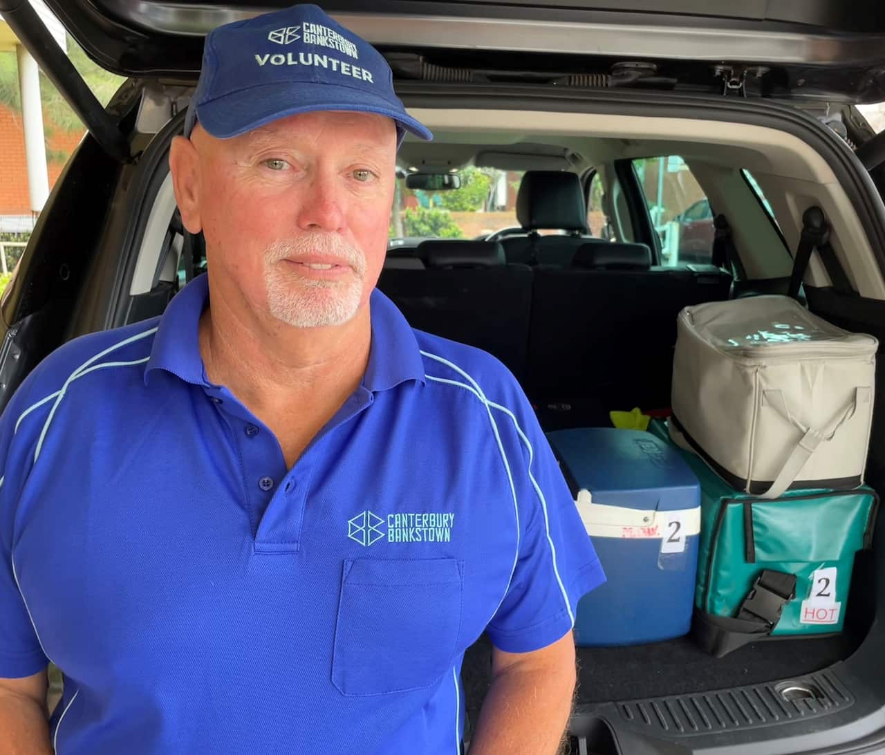Meals on Wheels volunteer Robert Cockle sitting at his open car boot.