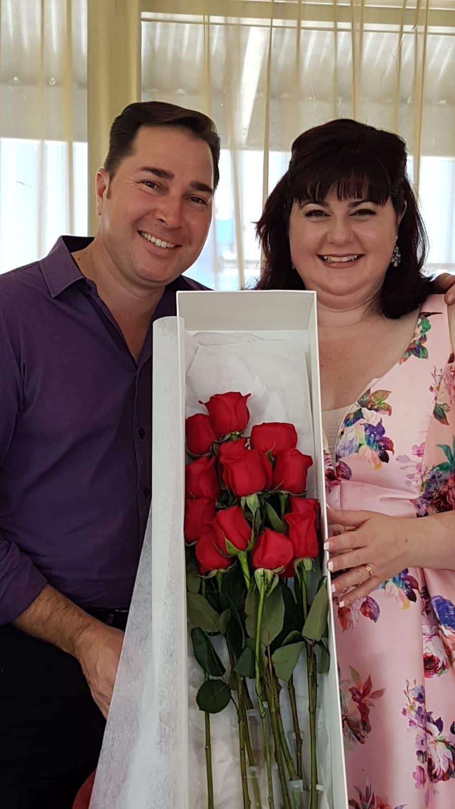 Sacha and Sherrie smiling and holding a box of roses. 