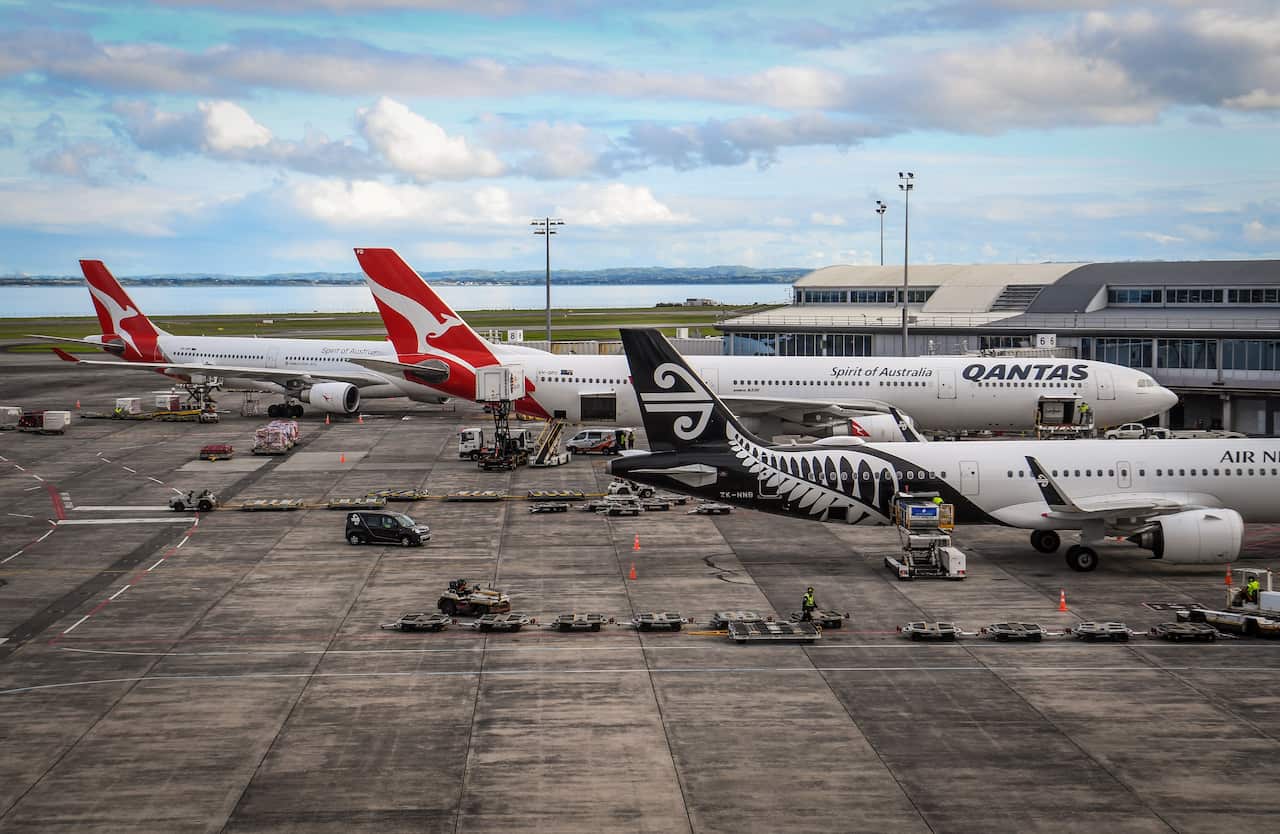 Two Qantas planes and one Air New Zealand plane are seen at an airport.