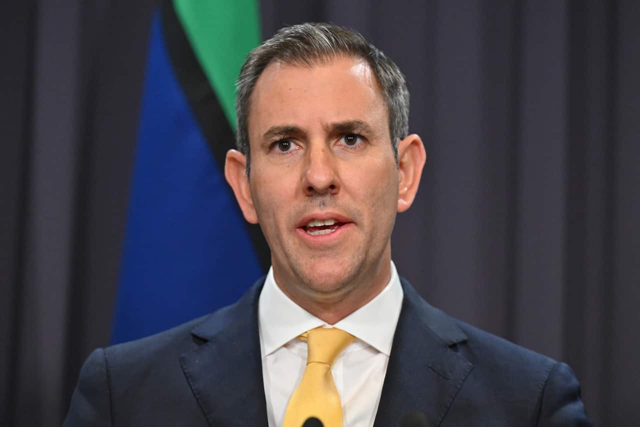 Jim Chalmers stands mid speech in a suit