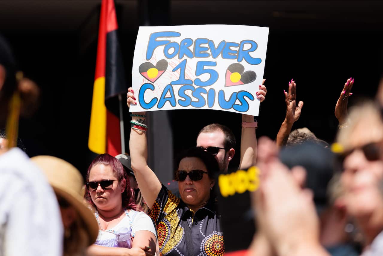 A woman hold up a sign during a rally for Cassius Turvey