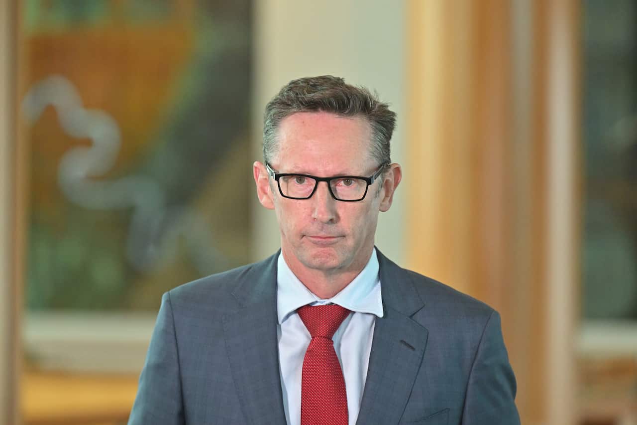 Stephen Jones in a grey suit, blue shirt and red tie.