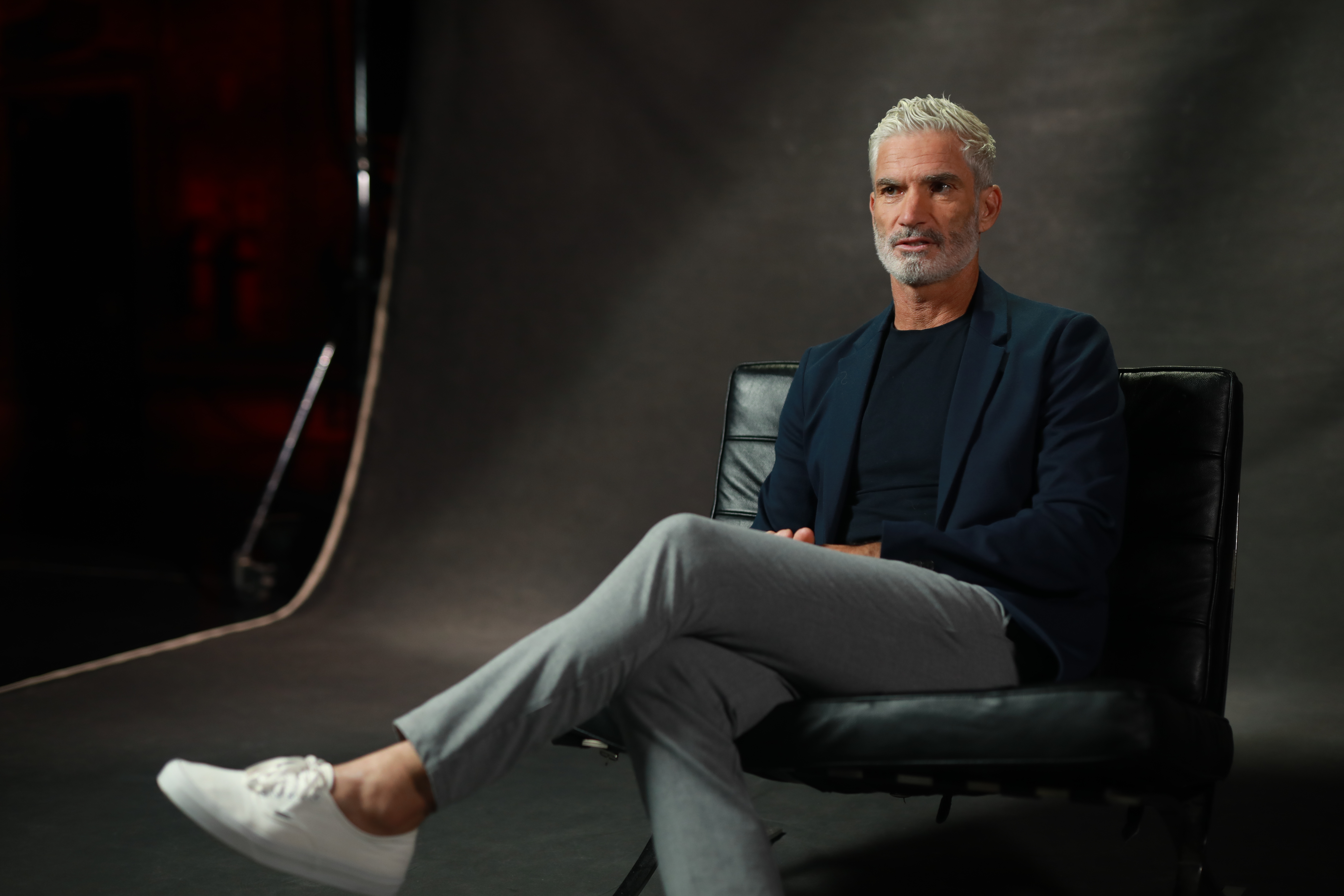 A man sits in a chair for an interview. 