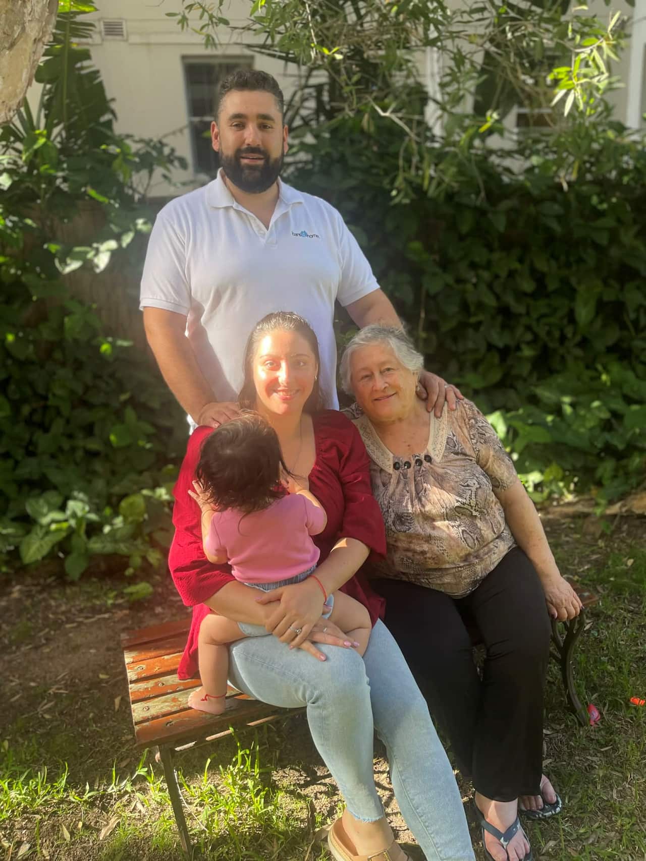 A couple in their 30s holding a baby and sitting next to an older woman
