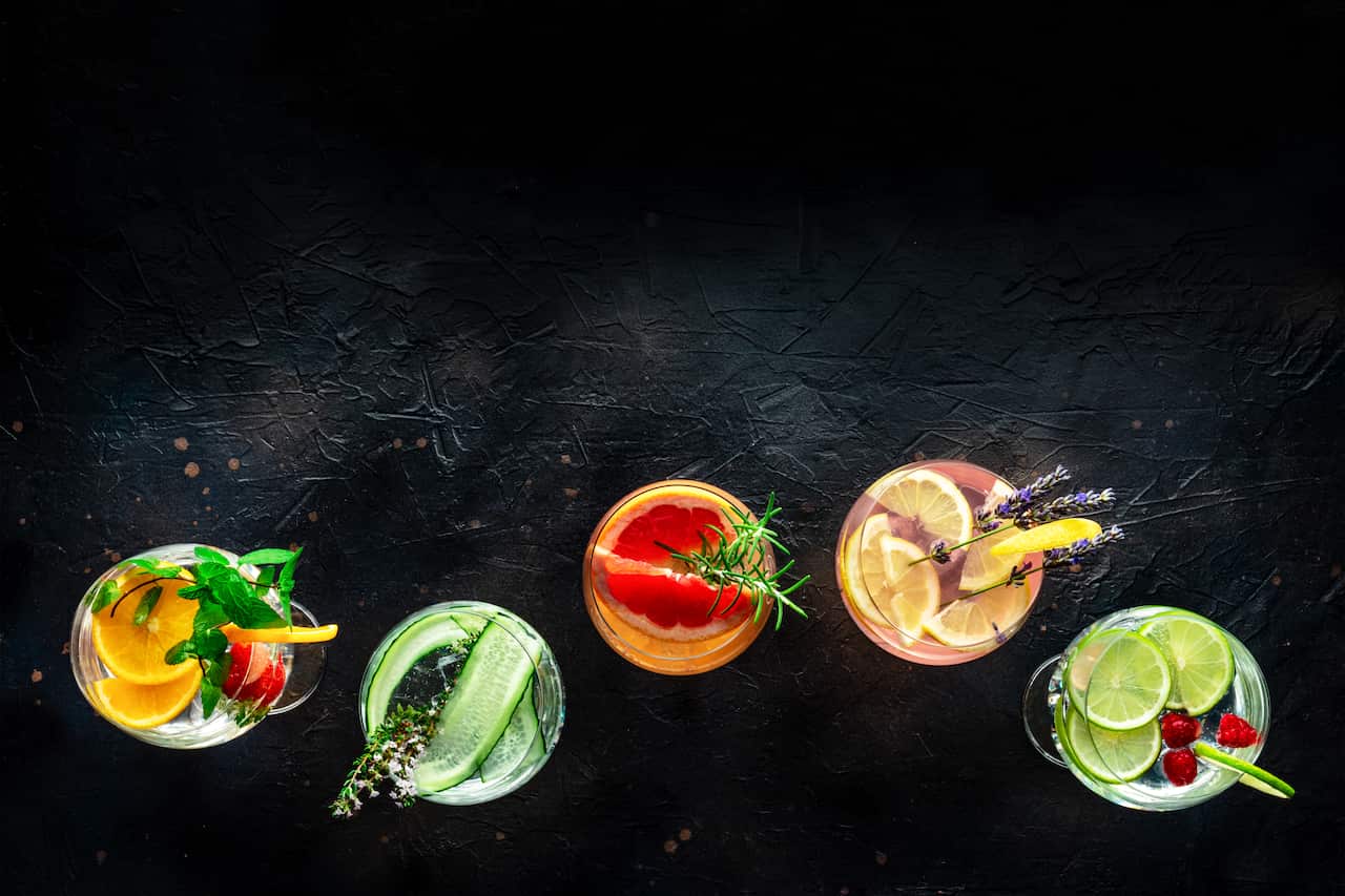 Overhead shot showing cocktails with fruit on a black background
