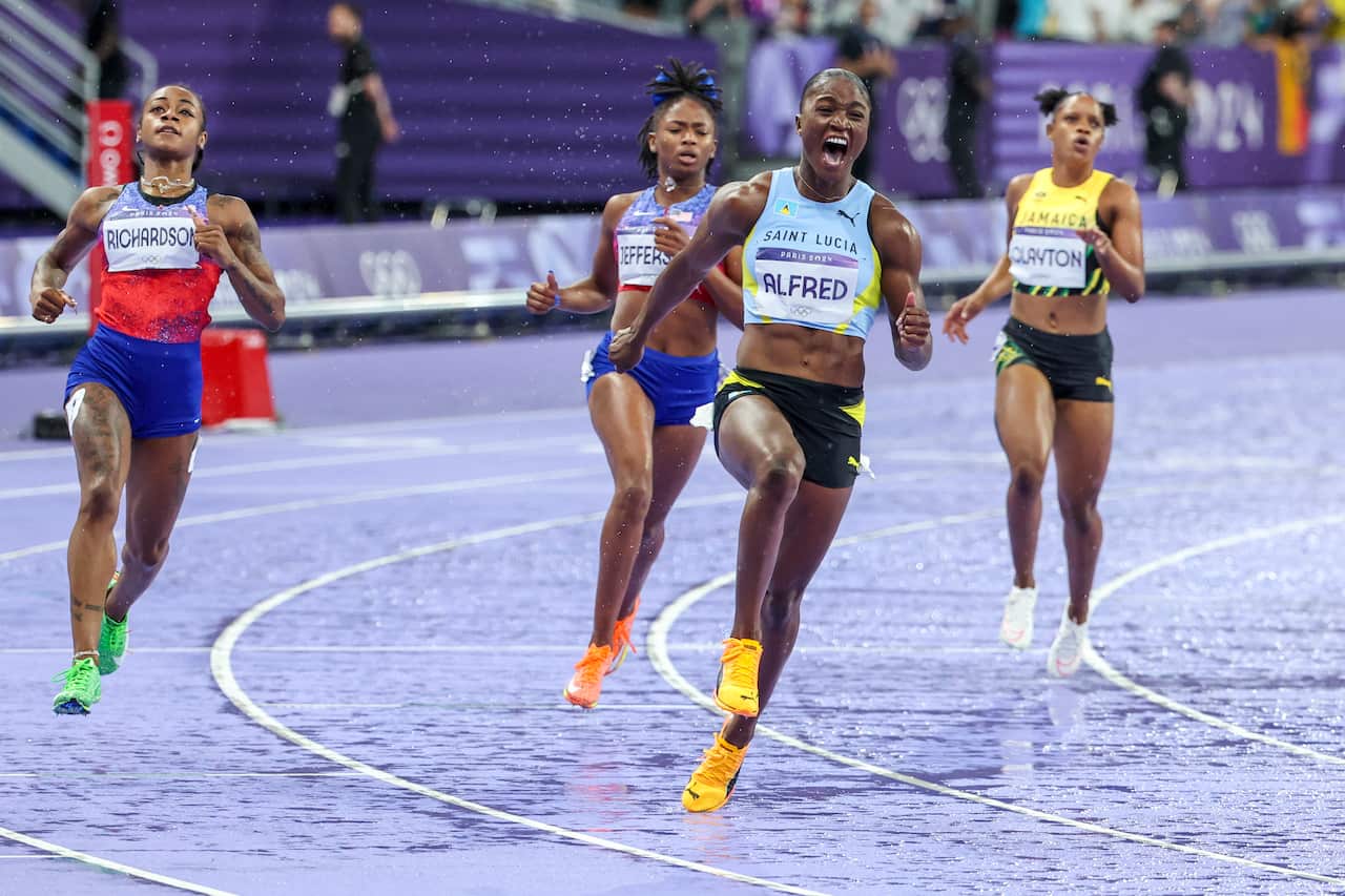 A group of women sprint on an athletics track 