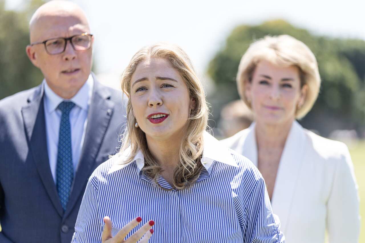A man in a blue suit and tie and white shirt stande next to a woman in a shirt with bue and white vertical stripes