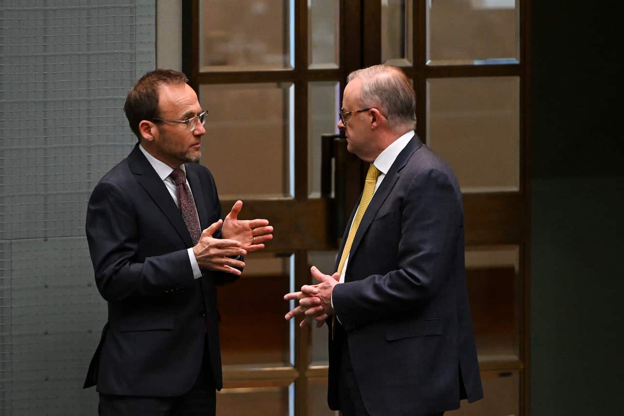 Two men in suits gesticulate as they talk.