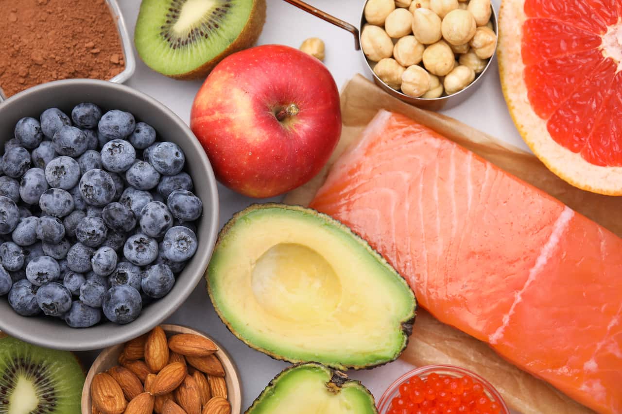 A selection of colourful healthy food laying on a white table.