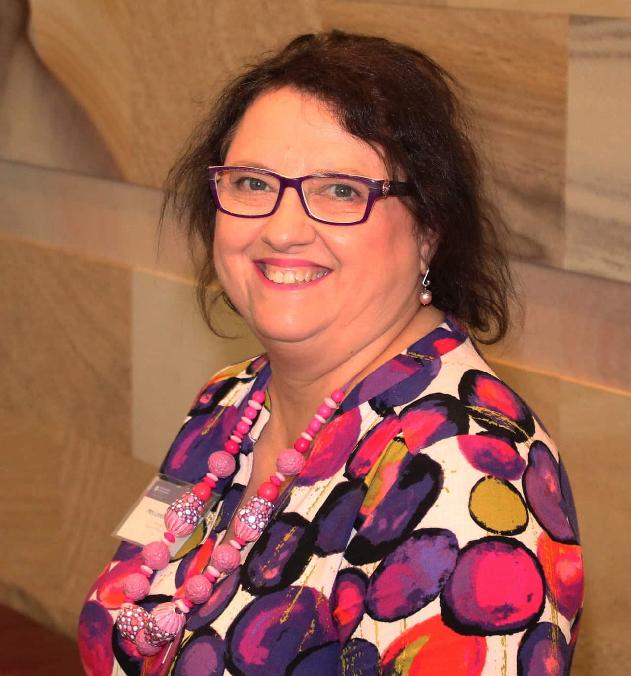 A lady smiling and looking down the barrel of the camera 