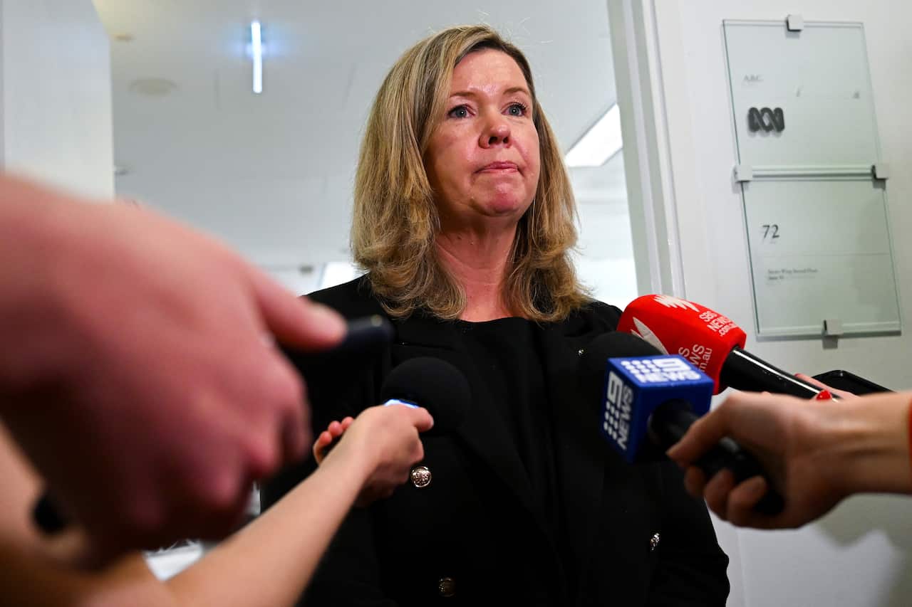 Woman speaking in front of multiple microphones.