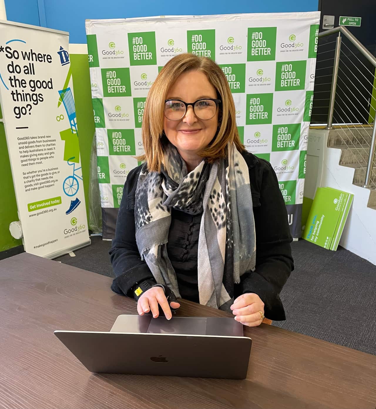 Good360 founder Alison Covington facing the camera sitting at a laptop computer.
