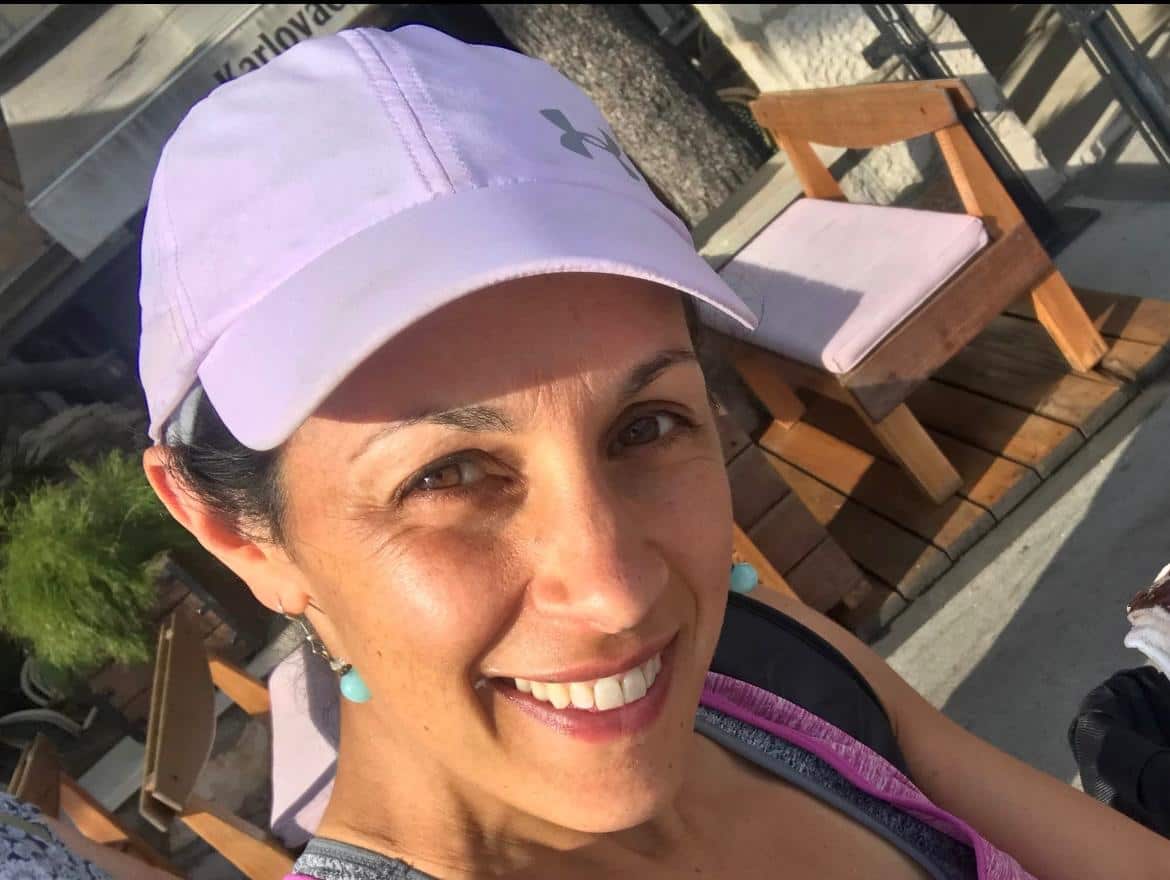 A selfie of a smiling woman in a baseball cap.